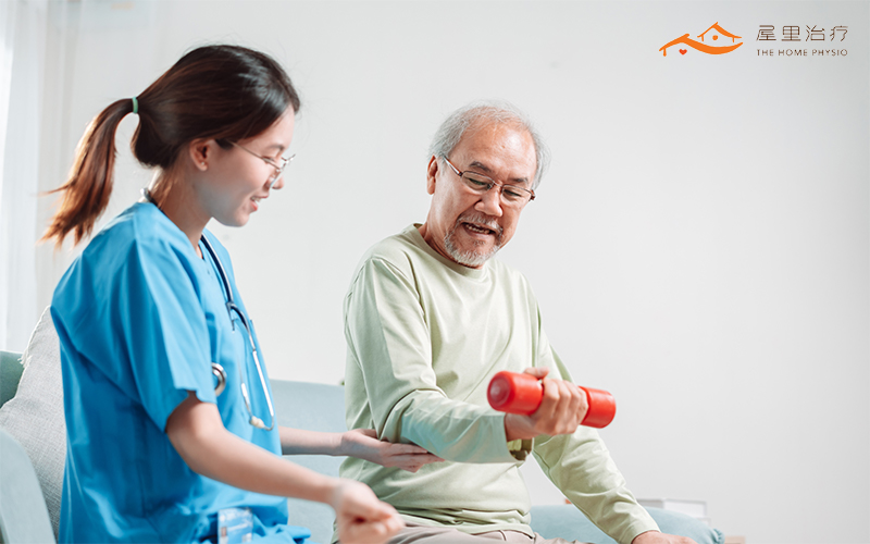 An elderly man having a physiotherapy session at home with a dumbbell