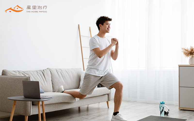 Man performing a lunging exercise at home, stepping forward and lowering into a bent-knee position to enhance balance and leg strength.