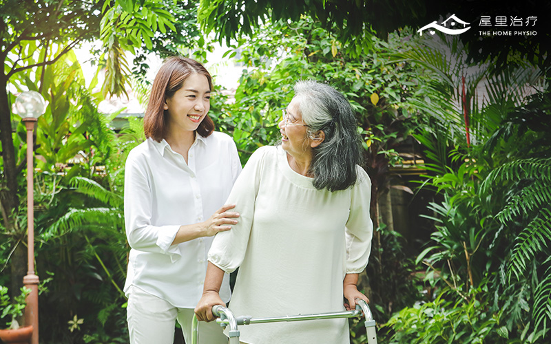 elderly woman with walking aid helped by a younger woman